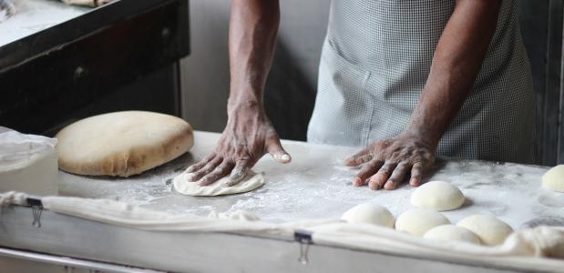 Een bakker kneedt het deeg