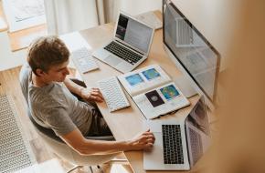 Man aan het werk achter 3 computers